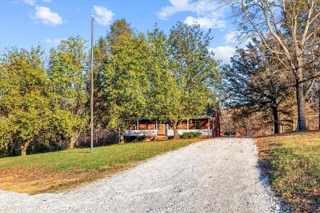 exterior space with gravel driveway and a front lawn