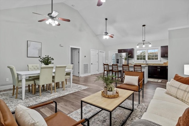 living room with high vaulted ceiling, wood finished floors, a ceiling fan, and baseboards