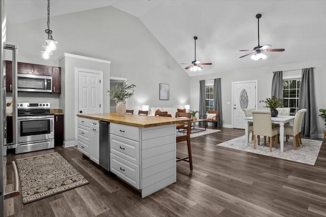 kitchen with white cabinets, dark wood-style floors, wood counters, stainless steel appliances, and a kitchen bar