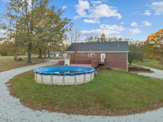 view of pool featuring a lawn, a wooden deck, and a covered pool