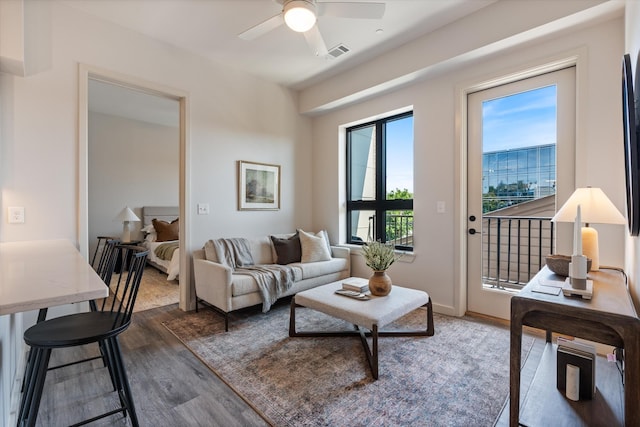 living room featuring ceiling fan, wood finished floors, visible vents, and baseboards