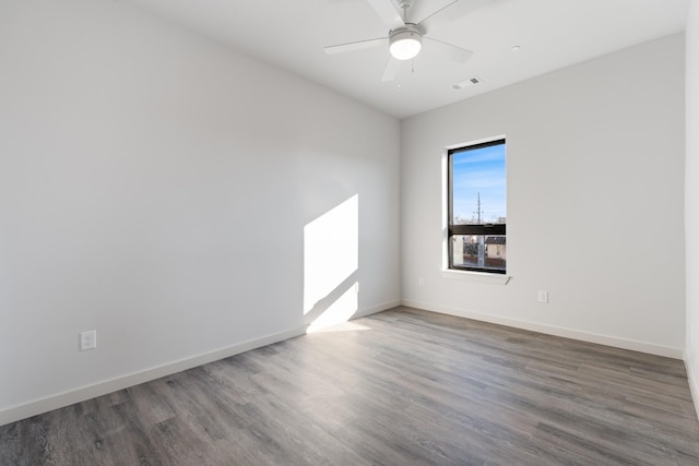 spare room with baseboards, visible vents, ceiling fan, and wood finished floors