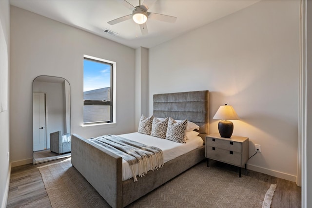 bedroom featuring ceiling fan, wood finished floors, visible vents, and baseboards