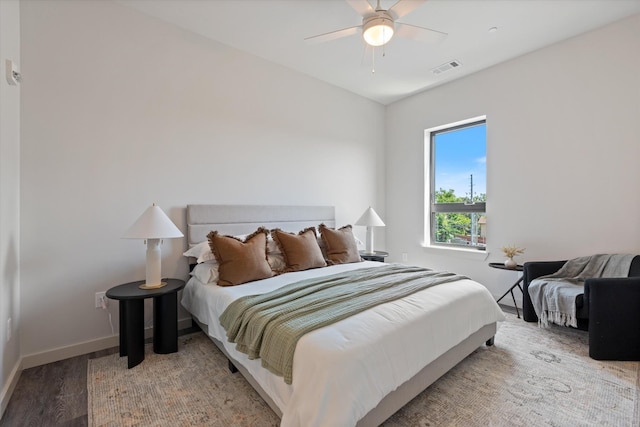 bedroom featuring a ceiling fan, wood finished floors, visible vents, and baseboards