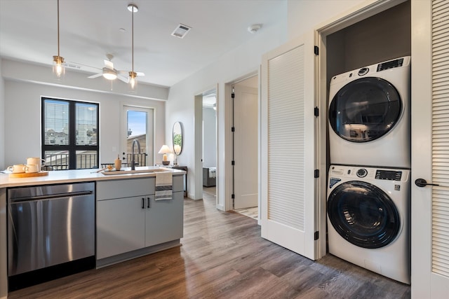 washroom with laundry area, a sink, visible vents, stacked washer / drying machine, and dark wood finished floors