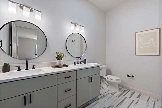 full bath with double vanity, a sink, toilet, and baseboards