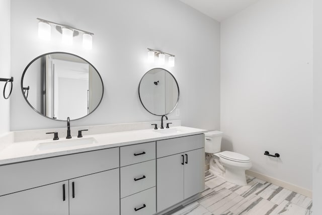 full bath featuring toilet, double vanity, baseboards, and a sink