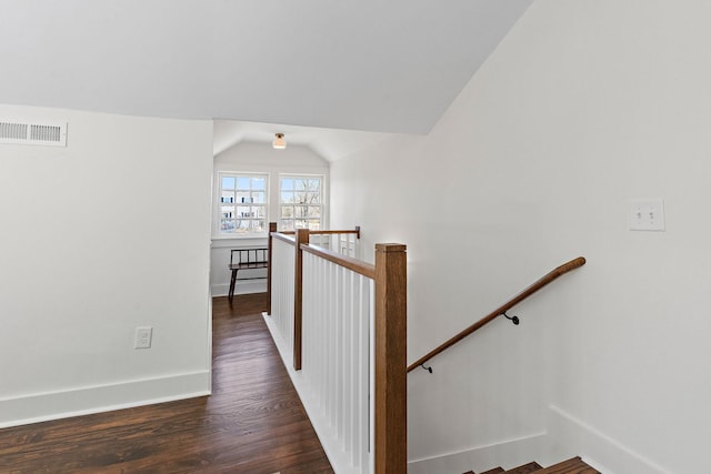 hallway with baseboards, visible vents, lofted ceiling, wood finished floors, and an upstairs landing