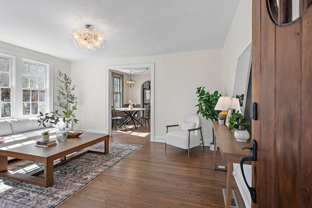 living room with an inviting chandelier, baseboards, and wood finished floors