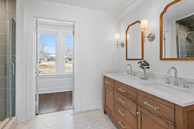 bathroom with double vanity, baseboards, an enclosed shower, and a sink