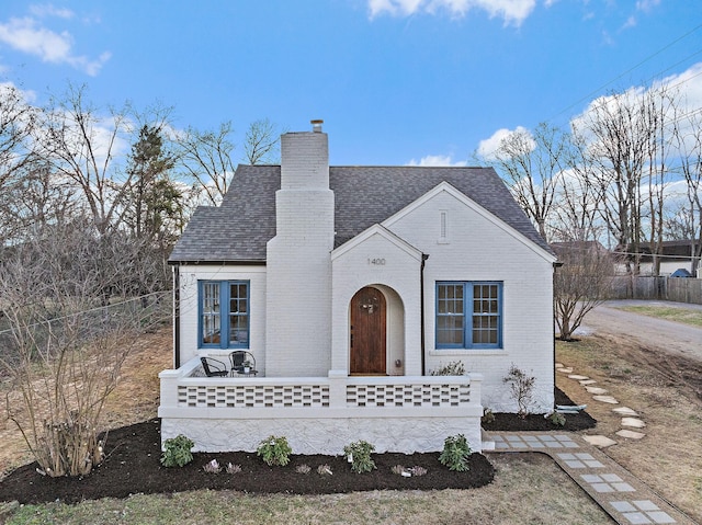 view of front of home featuring brick siding, a chimney, and a shingled roof