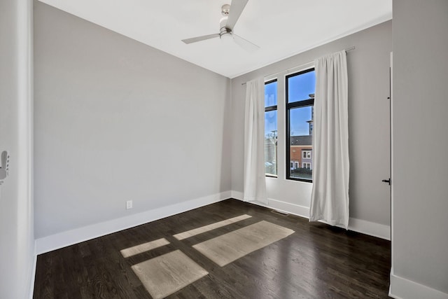 empty room with dark wood-style flooring, visible vents, ceiling fan, and baseboards