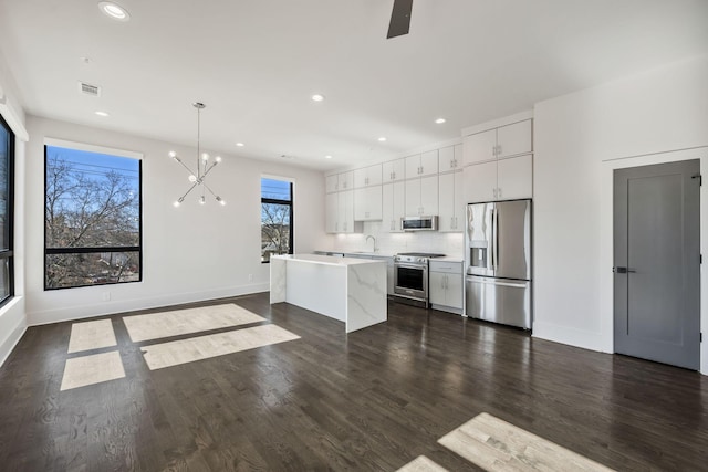 kitchen featuring dark wood-style floors, appliances with stainless steel finishes, white cabinets, and a sink