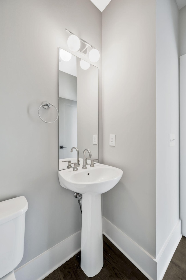 bathroom featuring a sink, wood finished floors, toilet, and baseboards