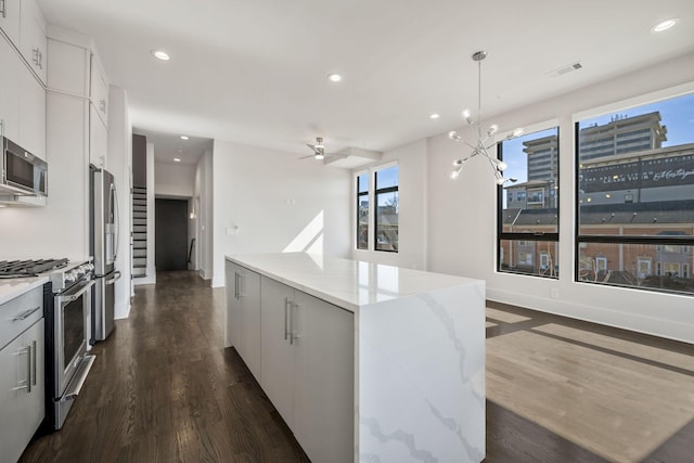 kitchen featuring recessed lighting, stainless steel appliances, dark wood-style flooring, hanging light fixtures, and a center island