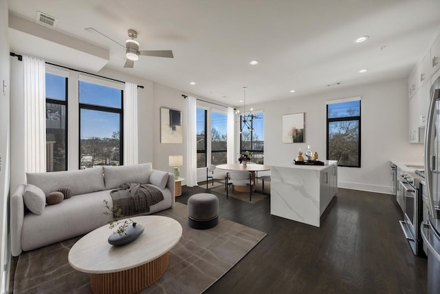 living area with dark wood-style floors, recessed lighting, visible vents, and plenty of natural light