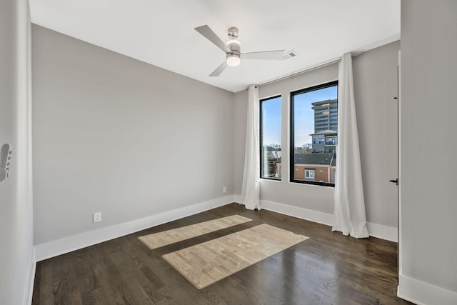 spare room with dark wood-type flooring, baseboards, and a ceiling fan