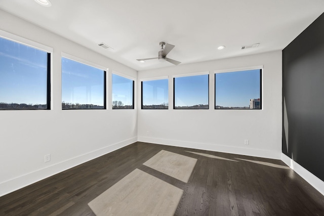 spare room with ceiling fan, wood finished floors, visible vents, and baseboards