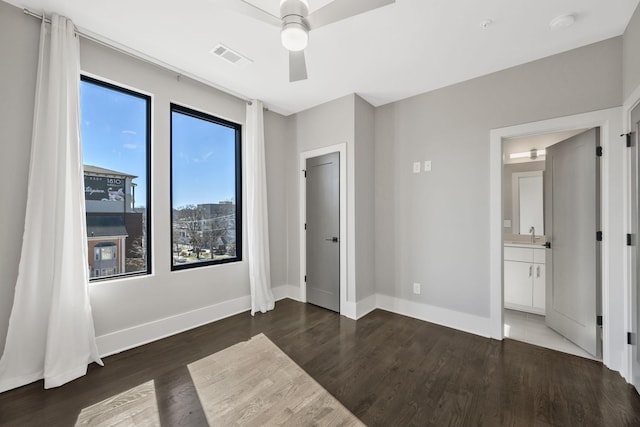 unfurnished bedroom featuring visible vents, baseboards, connected bathroom, ceiling fan, and wood finished floors