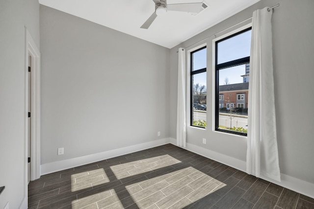 empty room with baseboards, a ceiling fan, and wood tiled floor