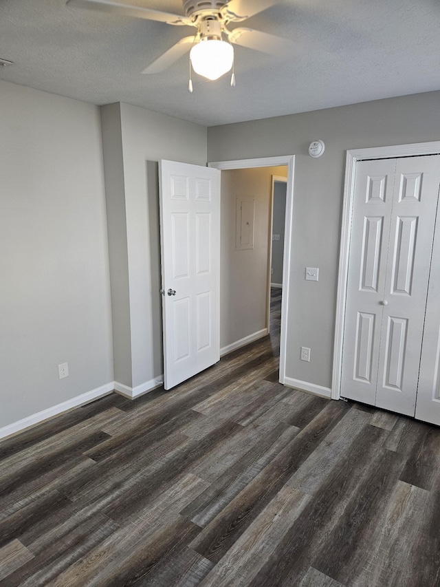 unfurnished bedroom featuring dark wood-style flooring, a closet, a ceiling fan, a textured ceiling, and baseboards