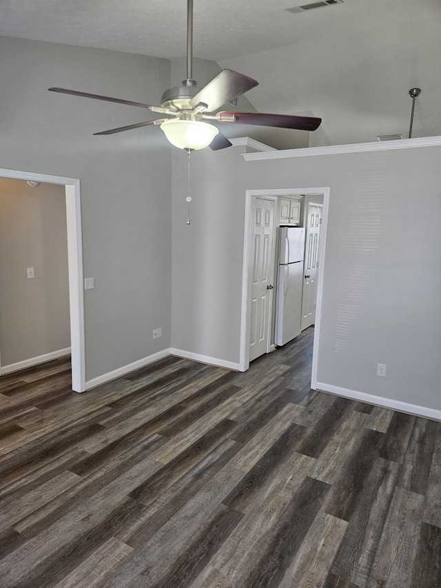 spare room with visible vents, vaulted ceiling, baseboards, and dark wood finished floors