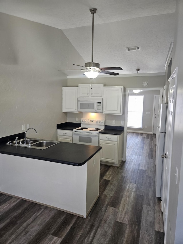 kitchen with white appliances, visible vents, dark countertops, white cabinetry, and a sink