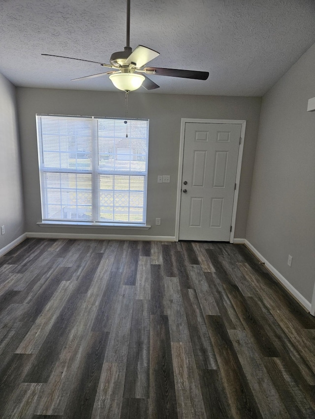 interior space featuring a ceiling fan, dark wood-style flooring, a textured ceiling, and baseboards