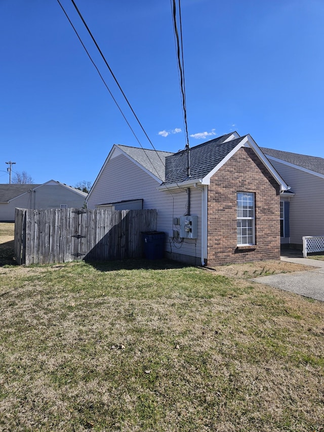 exterior space featuring brick siding, a lawn, and fence