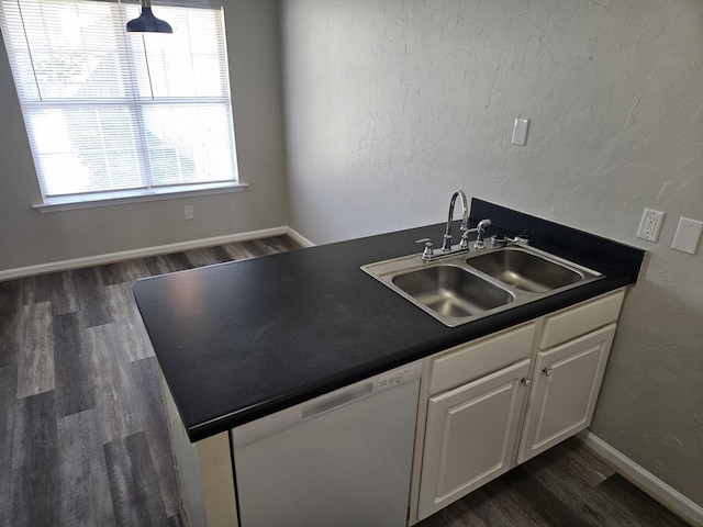 kitchen featuring dark countertops, white dishwasher, a sink, and white cabinetry