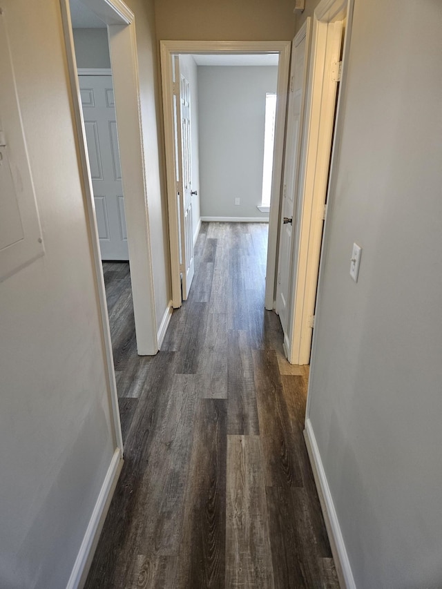 corridor featuring dark wood-style flooring and baseboards