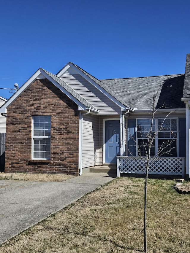 single story home with a front yard, roof with shingles, a chimney, and brick siding