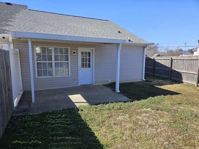 back of property featuring a yard, a patio area, fence, and roof with shingles