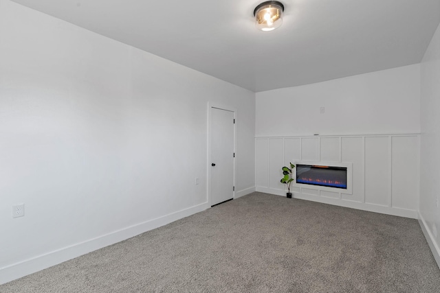 unfurnished living room featuring carpet floors, baseboards, and a glass covered fireplace