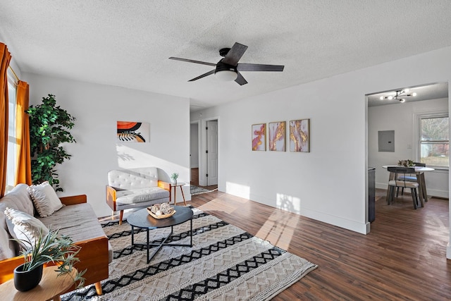 living area with a textured ceiling, ceiling fan, wood finished floors, baseboards, and electric panel