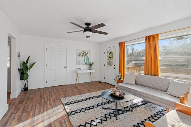 living room with a textured ceiling, wood finished floors, a ceiling fan, and baseboards