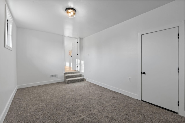 spare room featuring stairway, carpet, visible vents, and baseboards