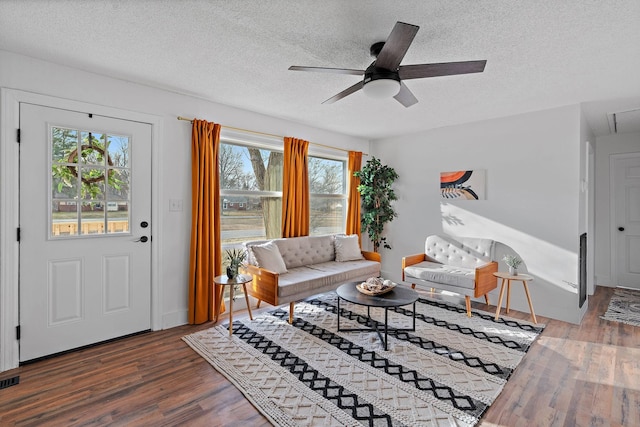 living room featuring a textured ceiling, ceiling fan, wood finished floors, and attic access