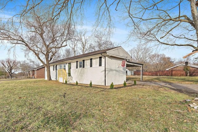 view of property exterior with driveway, fence, a yard, a carport, and brick siding