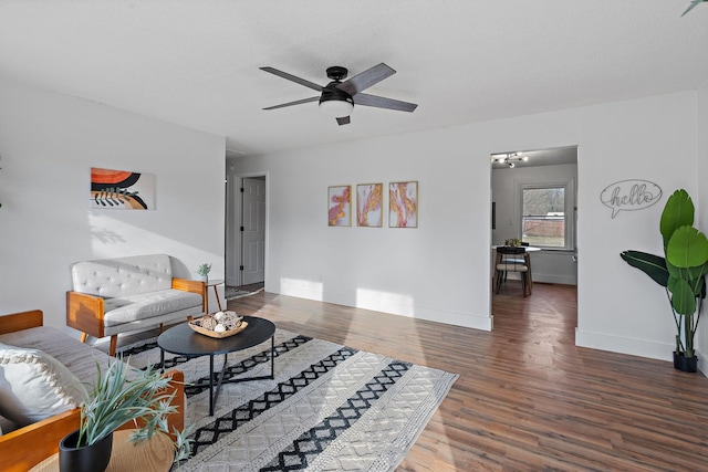 living room featuring a ceiling fan, baseboards, and wood finished floors