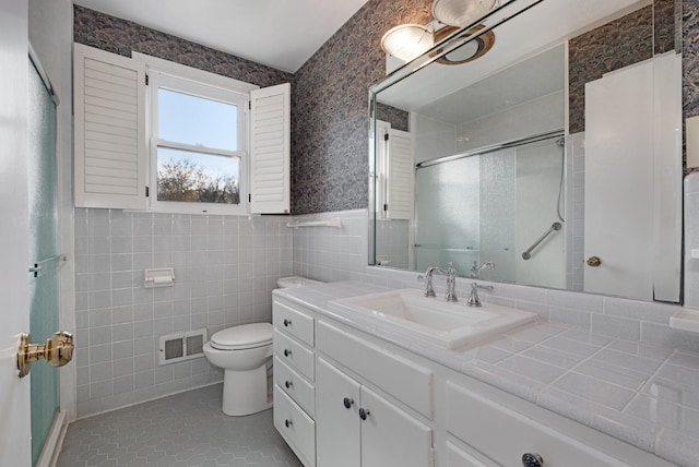 bathroom featuring toilet, tile patterned flooring, vanity, a shower stall, and tile walls