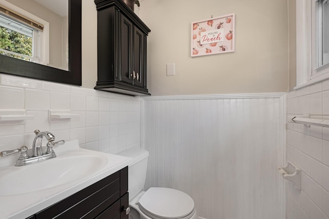 half bath featuring toilet, a wainscoted wall, and vanity