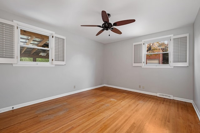 unfurnished room with ceiling fan, light wood-style flooring, visible vents, and baseboards