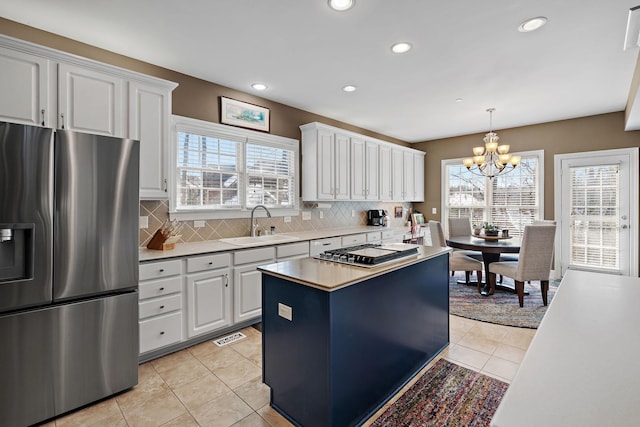 kitchen featuring light tile patterned floors, appliances with stainless steel finishes, a sink, and decorative backsplash