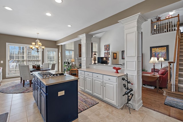 kitchen featuring decorative columns, stainless steel gas stovetop, white cabinetry, and light countertops