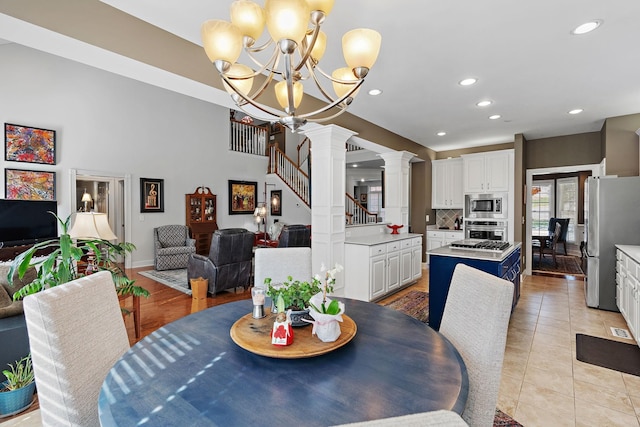 dining room with light tile patterned floors, recessed lighting, a notable chandelier, stairway, and decorative columns