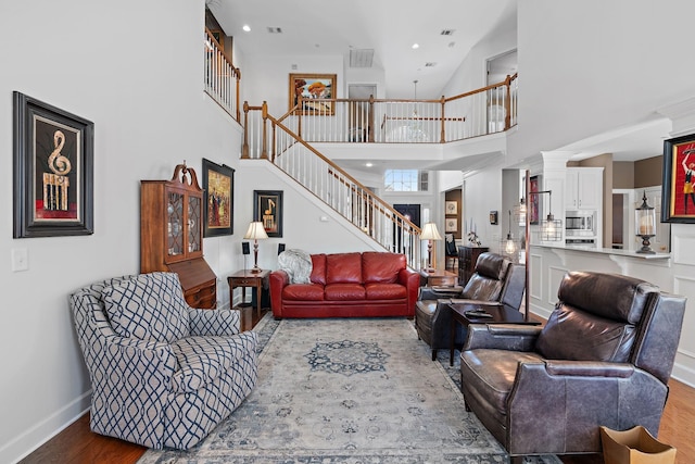 living area with a high ceiling, stairway, wood finished floors, and baseboards