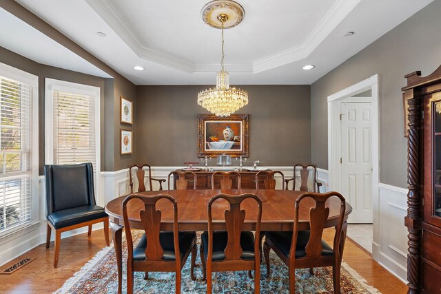 dining area featuring a wainscoted wall, a raised ceiling, visible vents, and a notable chandelier