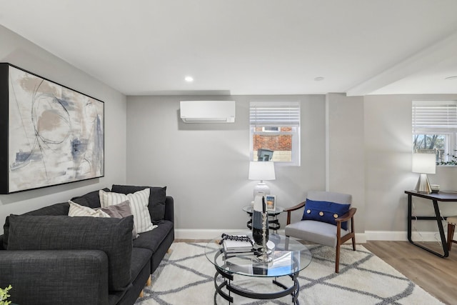 living area featuring light wood-style flooring, a wall mounted air conditioner, a wealth of natural light, and baseboards