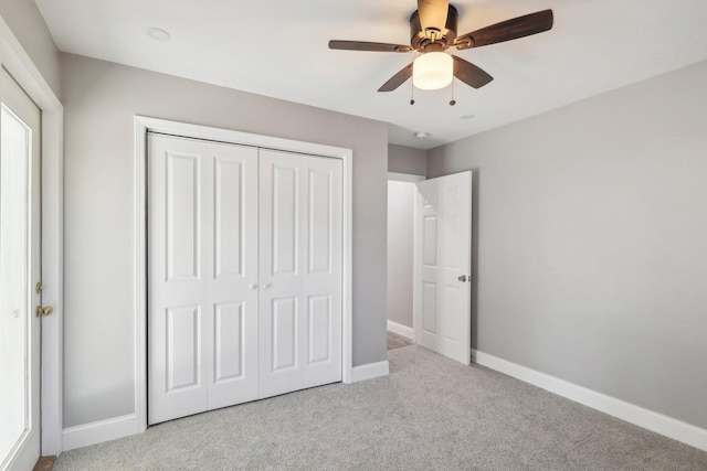 unfurnished bedroom with a closet, carpet, a ceiling fan, and baseboards